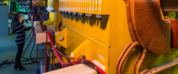 Young scientist in front of a quadrupole magnet